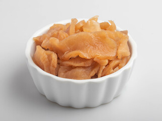 Pickled radish in a white cup on a white background.