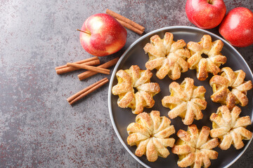 Autumn dessert Apple puff pastry with sugar and cinnamon close-up in a plate on the table. Horizontal top view from above