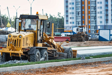 Road grader at the construction site. Powerful construction machine for ground leveling and excavation. Close-up. Professional construction equipment.