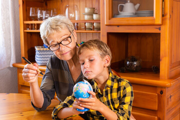 Homeschooling grandmother teaching smart boy, child in geography