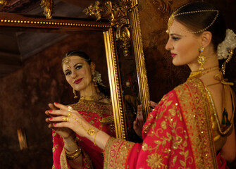 Female model Hindu Bride in saree, wearing gold and jasmine flower garlands in the hair near mirror