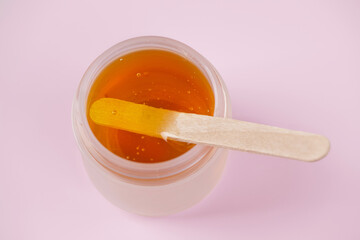 Golden sugar paste or wax for epilation on pink background. Sugaring and depilation.
