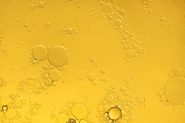Golden yellow abstract oil bubbles or face serum background. Oil and water bubbles macro...