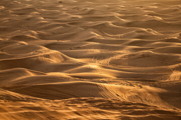 View of sand dunes criss crossed with vehicle tracks Dubai