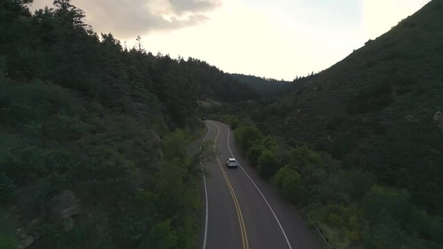 Tracking Aerial View of White Car Moving on Empty Road in American Countryside at Twilight, Drone Shot