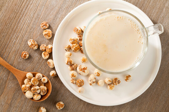 close up a glass of chufa milk with tiger nuts on wooden table. top view.