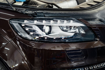 Obraz premium Car headlights and open hood in auto service garage