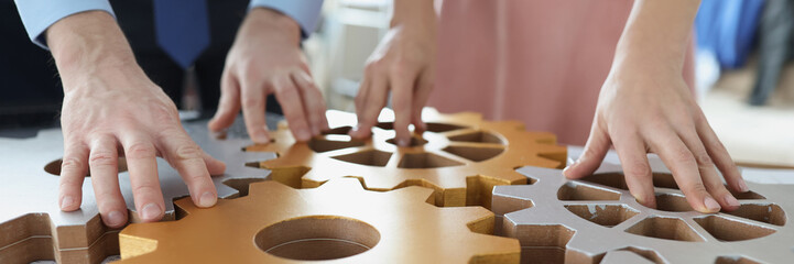 Businesspeople put wooden gears on workplace together, work in team
