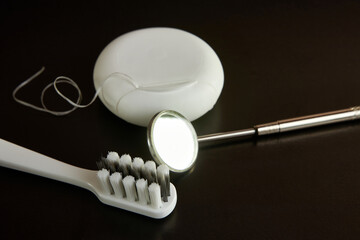 Dental mirror, dental floss and toothbrush on a black background. Dental care.