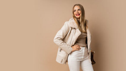 Winter studio fashion photo of elegant blond woman with red lips wearing trendy eco leather jacket , posing over beige background.