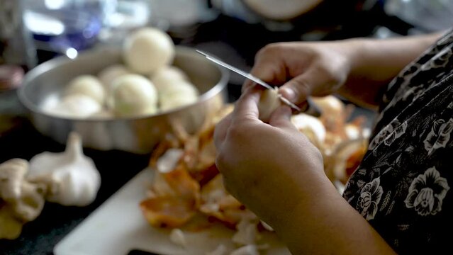 Close up shot of peeling garlic from husks in the home kitchen. A woman's hands peel garlic and put on the table.