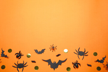 Flat lay composition with paper bats and spiders on orange background, space for text. Halloween decor