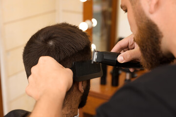 Professional hairdresser working with client in barbershop, closeup