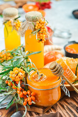 Freshly collected autumn honey in a jar. Sprigs of sea buckthorn and autumn berries. On a dark background. Side view.