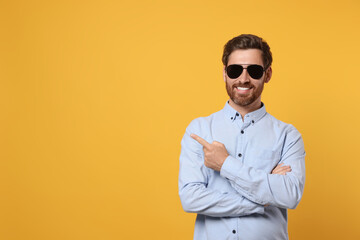 Portrait of smiling bearded man with stylish sunglasses on orange background. Space for text