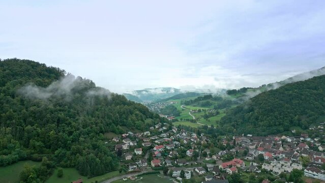 Static drone footage of a village in Switzerland. Road traffic and fog in autumn.
