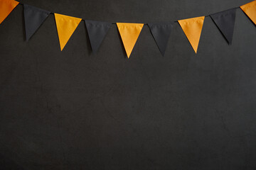 Halloween garland of black and orange flags on a dark background with space for text