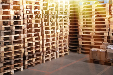 Many empty wooden pallets stacked in warehouse