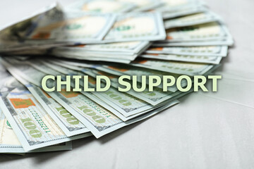Child support concept. Many dollar banknotes on white wooden background, closeup