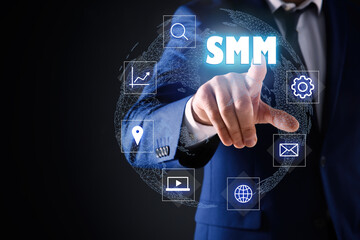 Social media marketing concept. Man touching virtual icon SMM against dark background, focus on hand