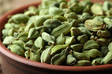 Bowl of dry green cardamom pods, closeup