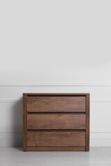 Wooden chest of drawers near white wall indoors, space for text