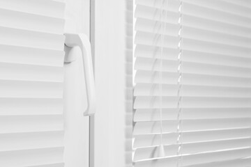 Window with closed white horizontal blinds indoors, closeup