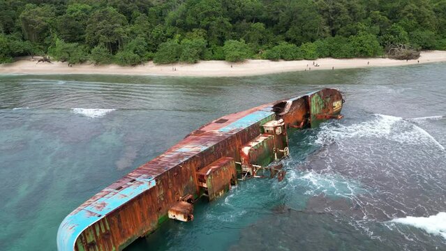Rusty Shipwreck Laying on its Side as Waves Crash in Pangandaran, Indonesia