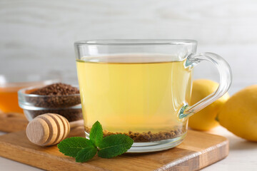 Cup of aromatic buckwheat tea, mint and granules on white table, closeup
