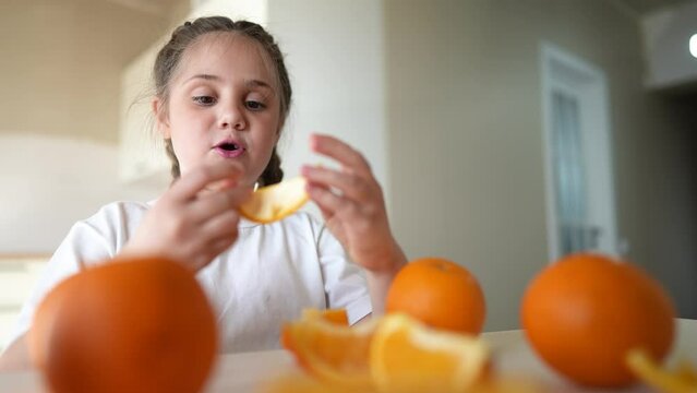 girl child eating oranges. happy family dream fruit healthy food kid concept. little girl daughter eating oranges at the table in the kitchen indoors. juicy fruits oranges are for a healthy diet