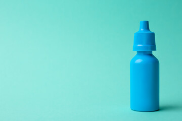 Bottle of medical drops on turquoise background. Space for text