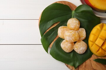 Flat lay composition with delicious mochi and mango on white wooden table, space of text....