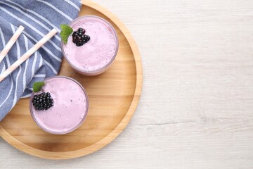 Delicious blackberry smoothie in glasses on white wooden table, top view. Space for text