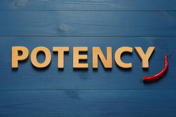 Word Potency made of letters and chili pepper on blue wooden table, flat lay