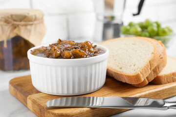 Delicious gooseberry jam and slices of bread on white table