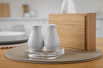White ceramic salt and pepper shakers on wooden table