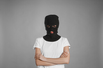 Woman wearing knitted balaclava on grey background