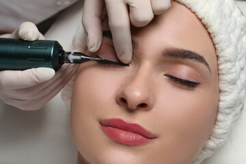 Young woman undergoing procedure of permanent eye makeup, closeup - obrazy, fototapety, plakaty