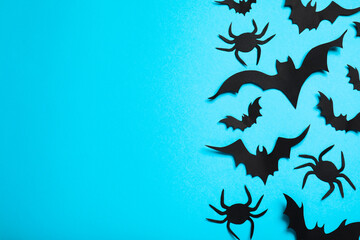Flat lay composition with paper bats and spiders on light blue background, space for text. Halloween decor