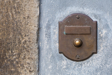 Antique brass doorbell with blank nameplate on the rock wall of a building