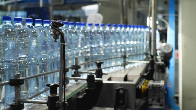 Bottles with a volume of 1.5 liters of water moves along the conveyor. Production of mineral water in the shop of the food industry plant. Slow motion