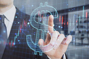 businessman hand pointing at creative glowing dollar sign hologram with forex chart on blurry...