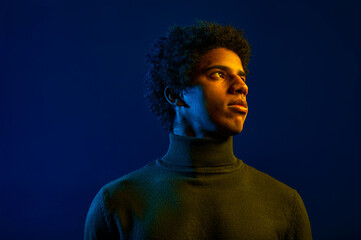 Young serious man looking away over dark studio background