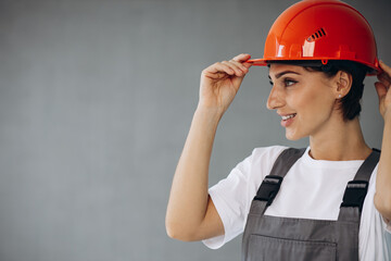 Woman builder in helmet wearing grey overalls