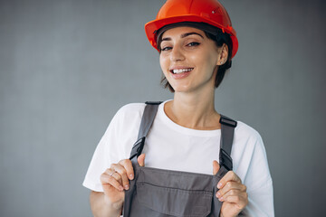 Woman builder in helmet wearing grey overalls