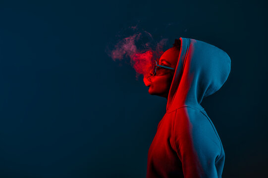 Casual hipster woman in hood blowing smoke