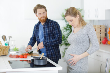 portrait of happy pregnant couple cooking in kitchen