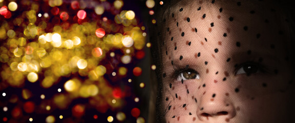 Pretty teenager girl with elegance veil covered face enchanted looking up on festive lights....