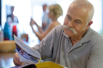 an elderly man reading magazine