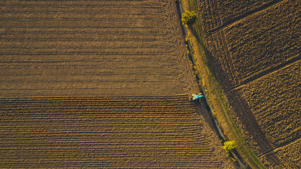 aerial view of farmer driving tractor deep plowing land at sunset, Piacenza, Italy 